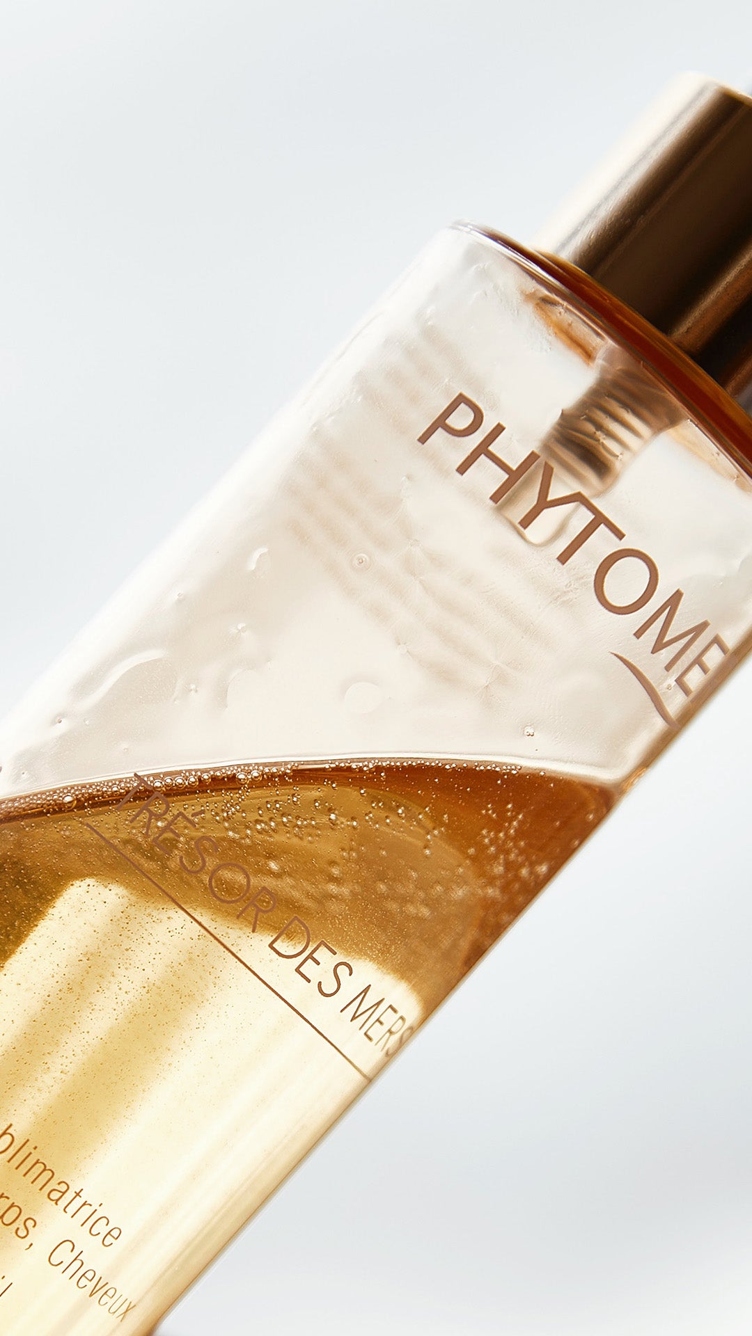 Close-up of a Phytome product bottle with gold and white design on a light gray background