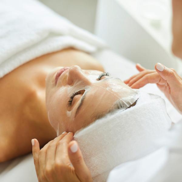 A person lying down with a collagen fibre mask on their face, potentially containing Aloe Vera for skin recovery.