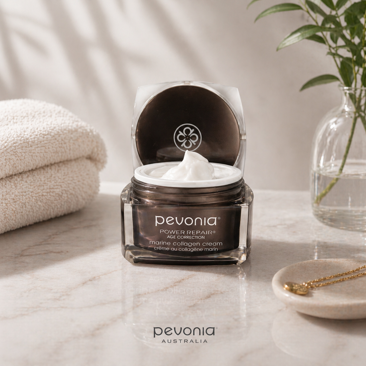 Pevonia skincare jar on a marble surface with a plant and towel in the background
