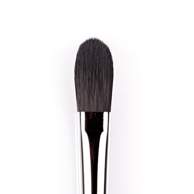 A close-up image of a large concealer brush with a flat, rectangular head and a silver handle.