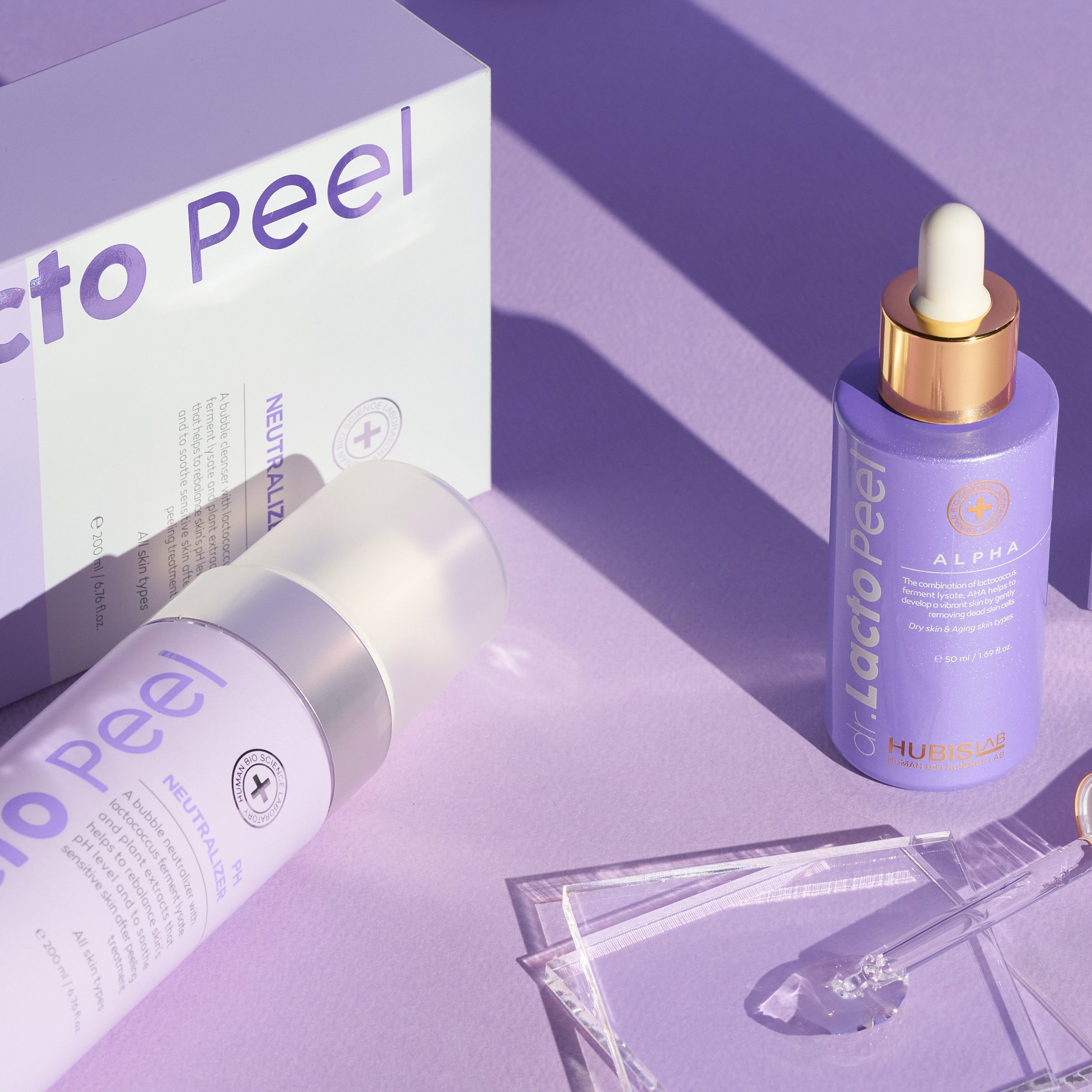 Hubislab Dr. Lacto Peel Alpha with Neutralizer skincare products including a dropper bottle and packaging on a purple background
