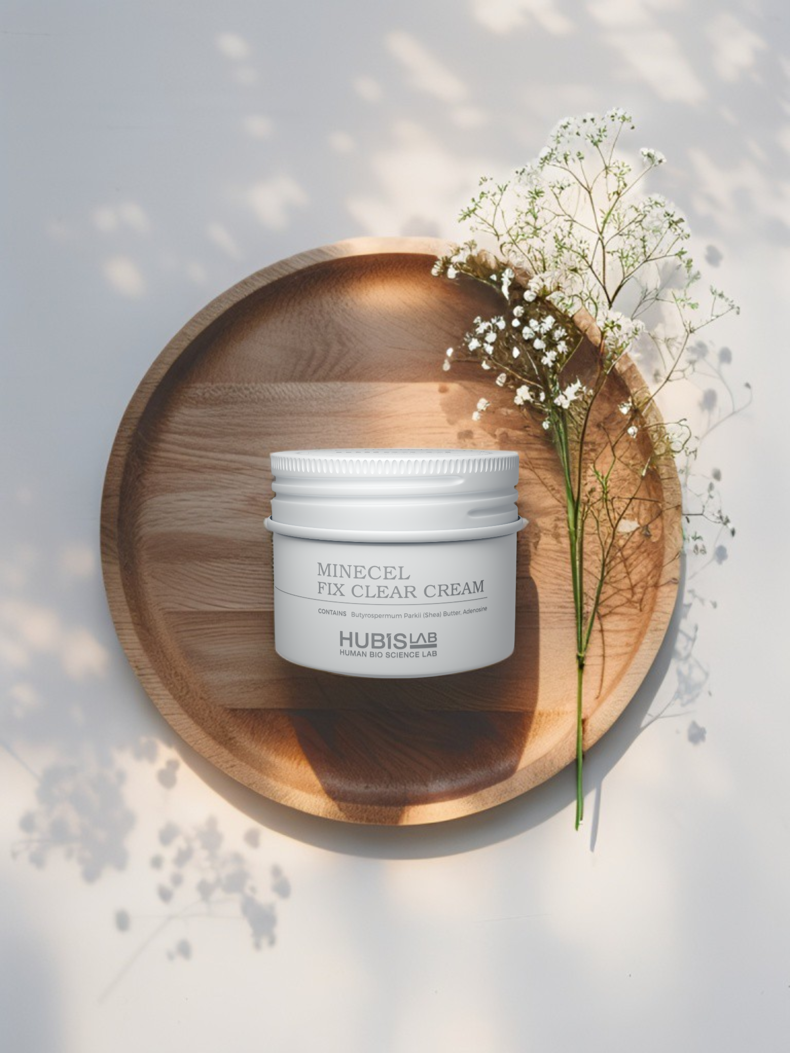 Jar of cream on a wooden plate with flowers on a light background
