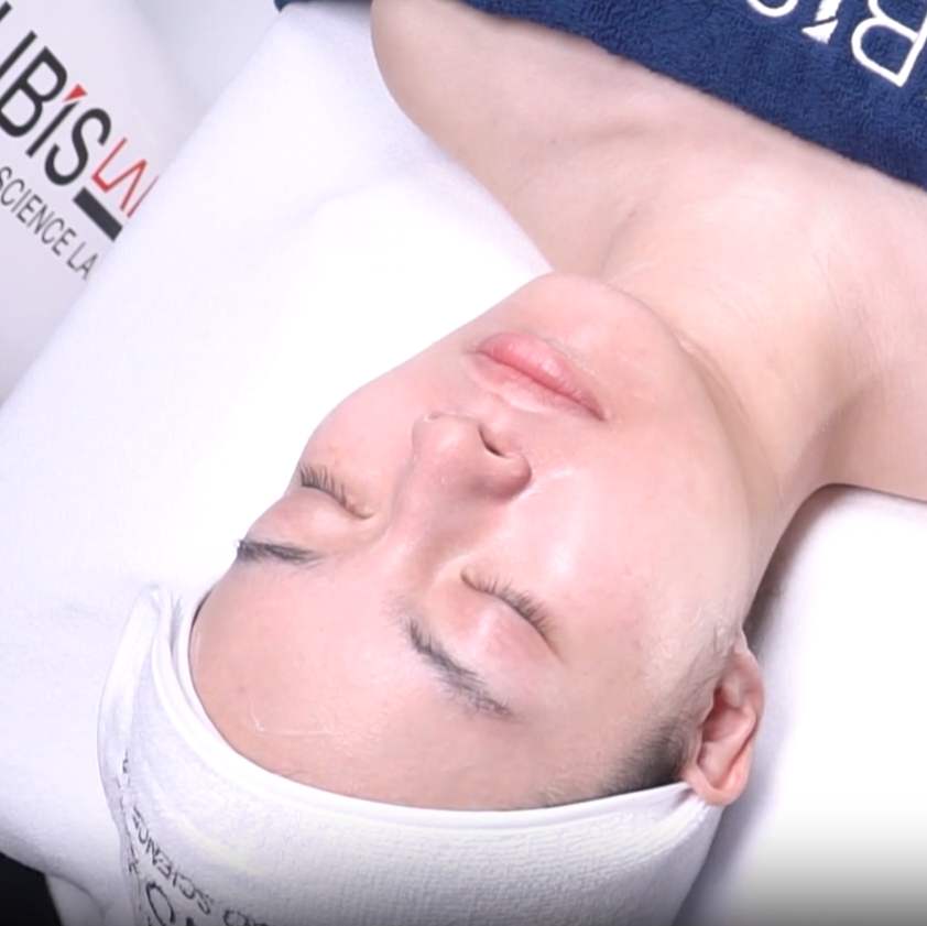 Person lying on a white pillow with 'Bisous' branding, eyes closed.
