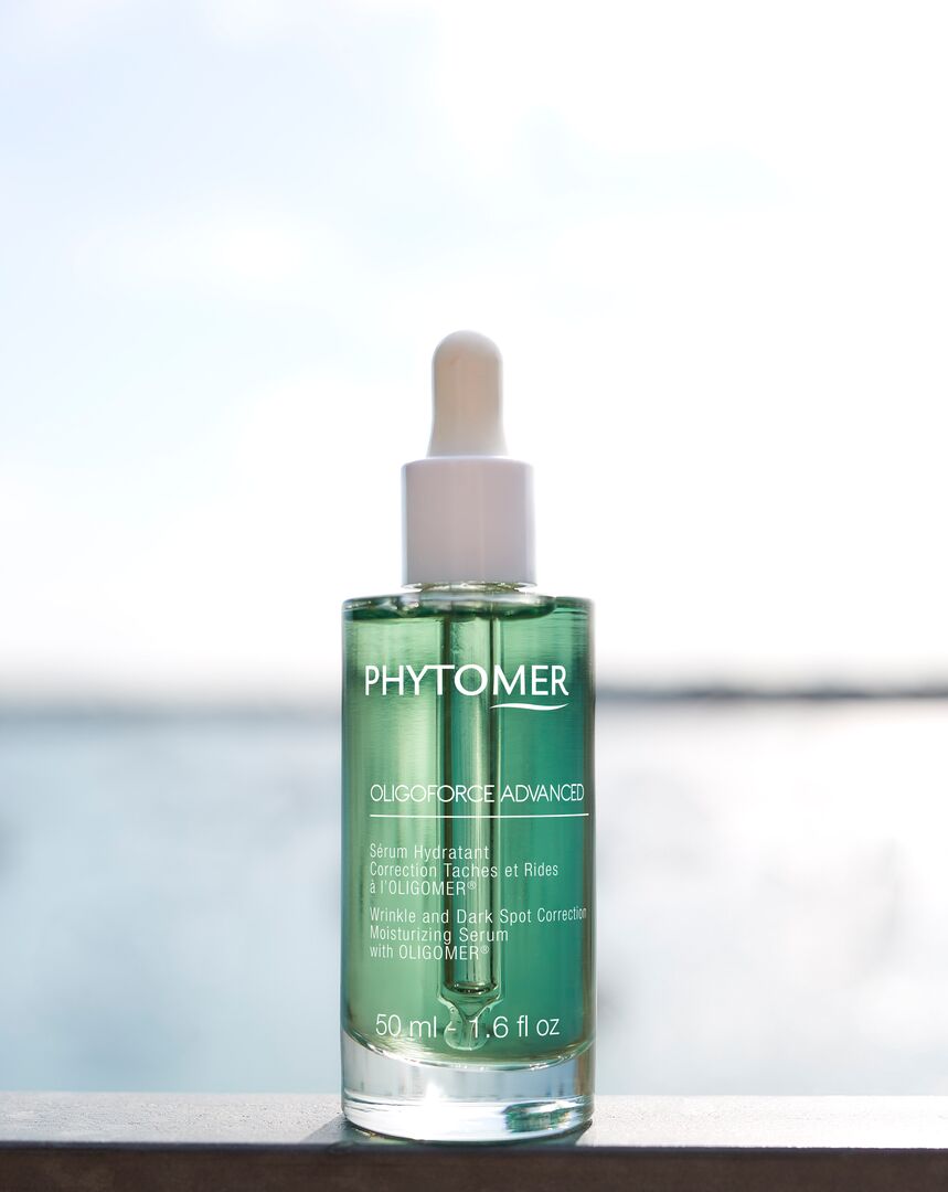 Phytomer skincare serum bottle on a reflective surface with a blurred background