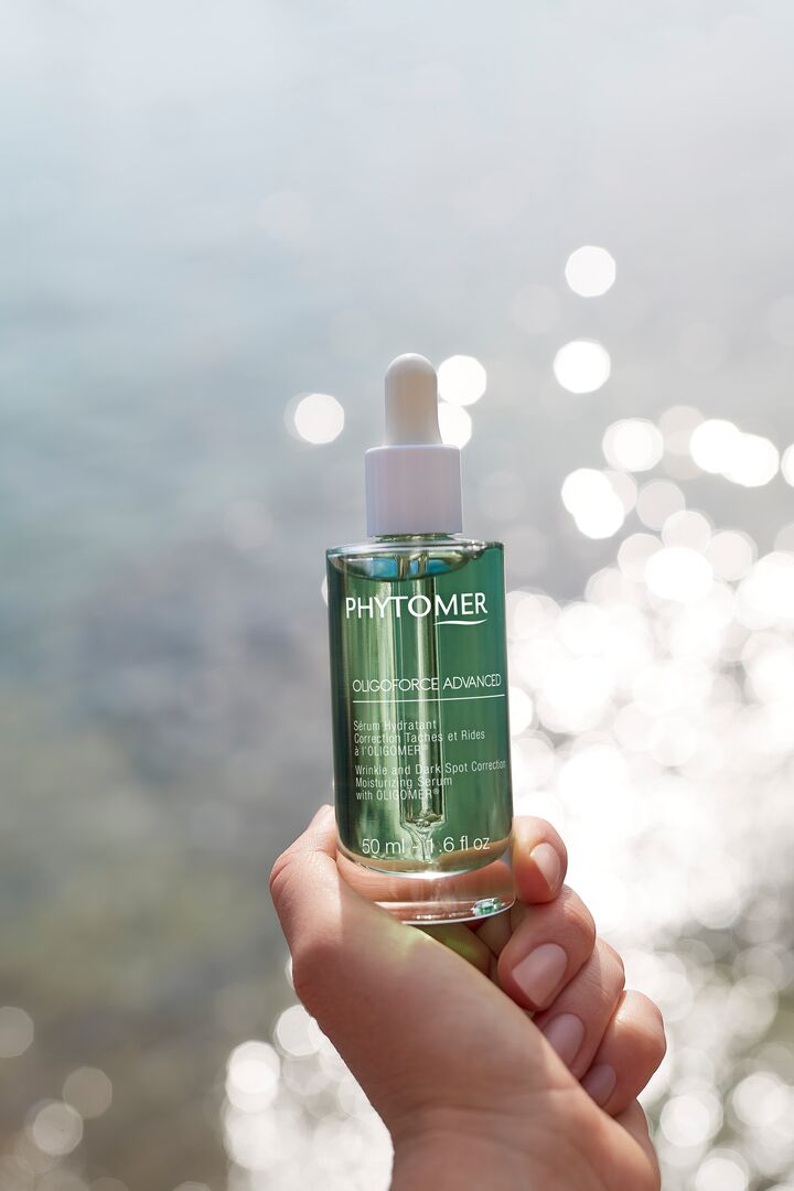 Hand holding a Phytomer skincare serum with a blurred natural background
