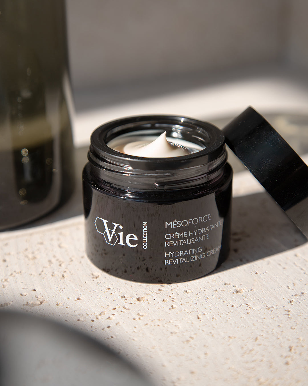 Jar of Vie mesoforce cream on a textured surface with a blurred background