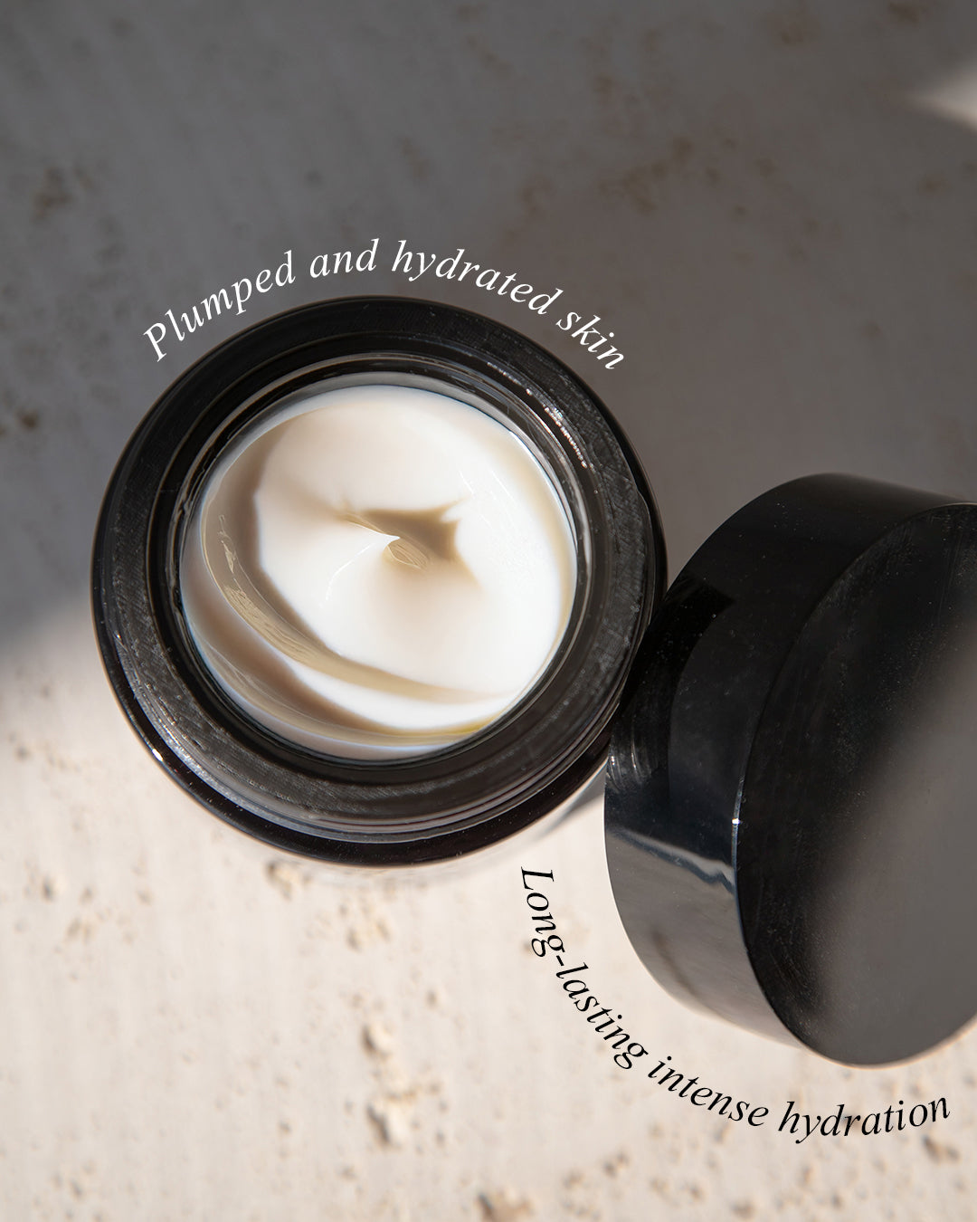Black jar of cream with white cream inside, on a textured surface.