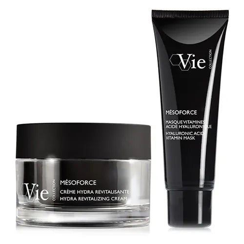 Two Vie Collection skincare products from the Mésoforce range displayed on a light grey background: a clear glass jar of Hydra Revitalizing Cream with a matte black lid beside a black tube of Hyaluronic Acid Vitamin Mask. The products are designed for hydration, radiance and skin revitalisation.