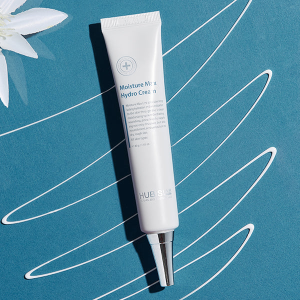 Tube of HUEMO Moisture Mix Hydro Cream on a blue background with white floral elements