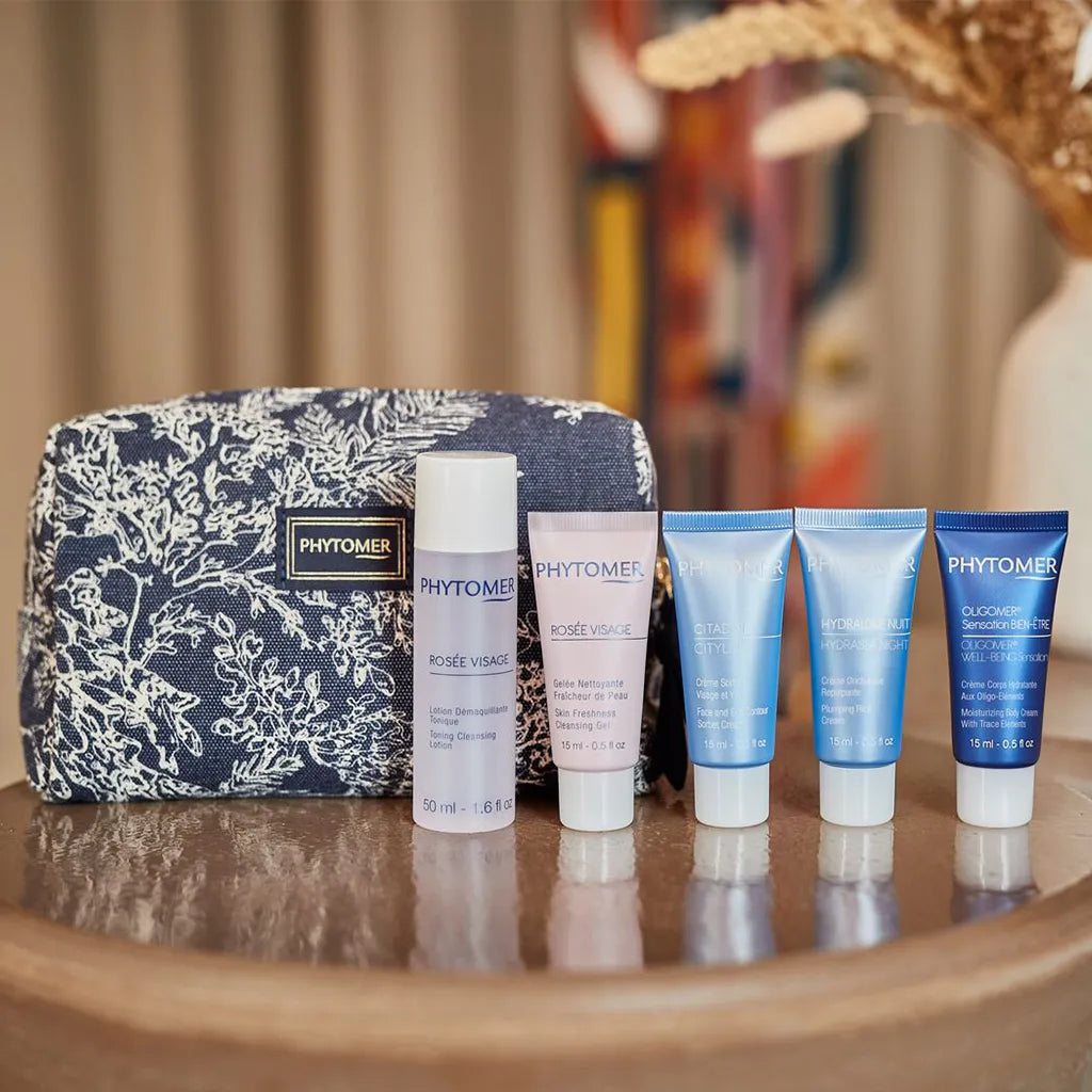 Phytomer skincare products including a pouch on a wooden surface.