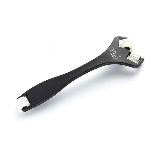 A black face shaper tool with white bristles and a metal component.
