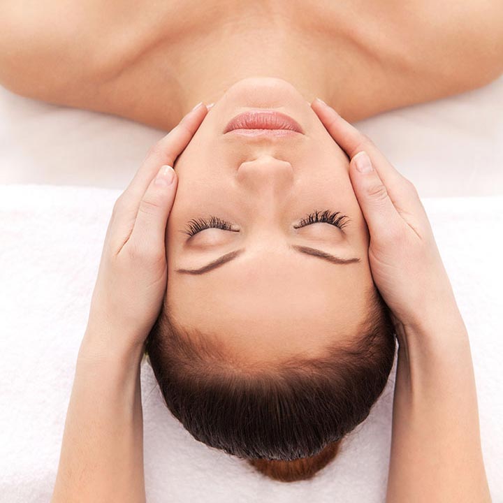 Person receiving a head massage with a neutral background