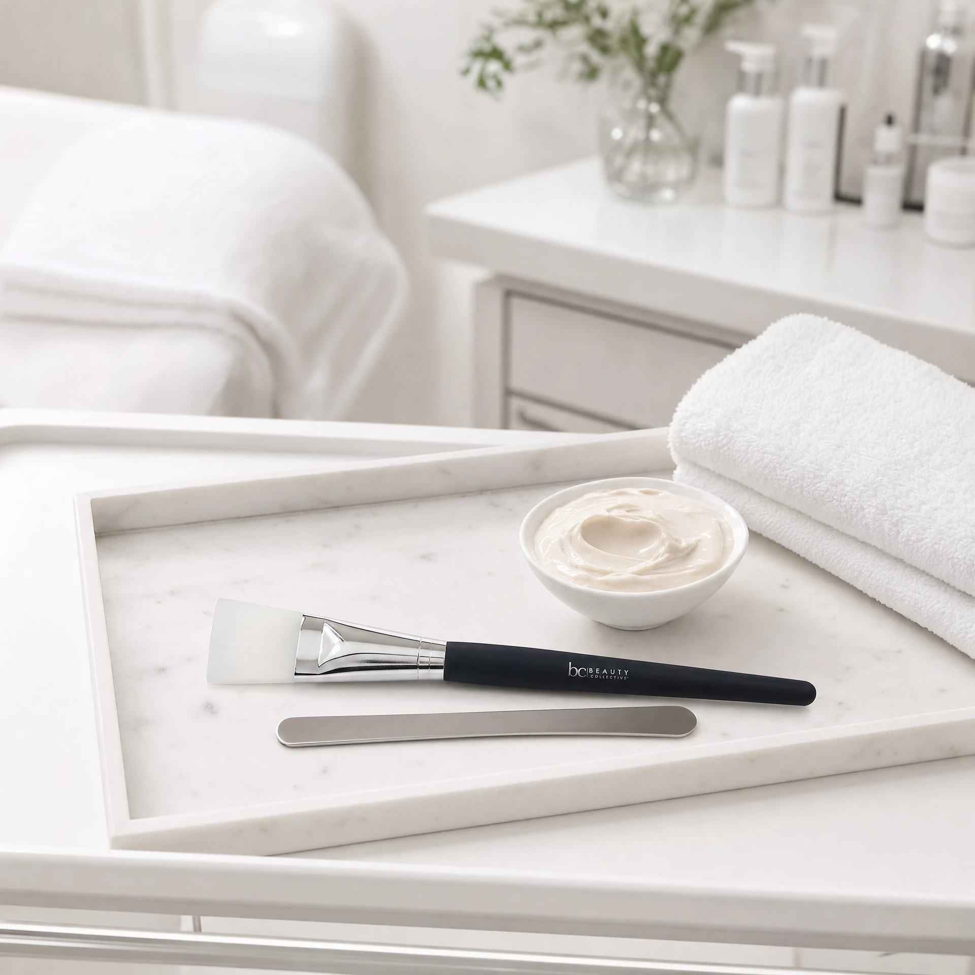 Beauty Collective Face Mask Brush on marble treatment tray with mask bowl, spatula and white towels in professional beauty clinic treatment room