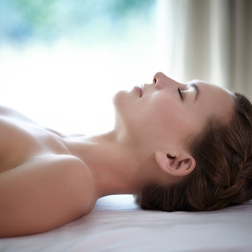 A person lying down with their eyes closed, presumably relaxing or receiving a skincare treatment.