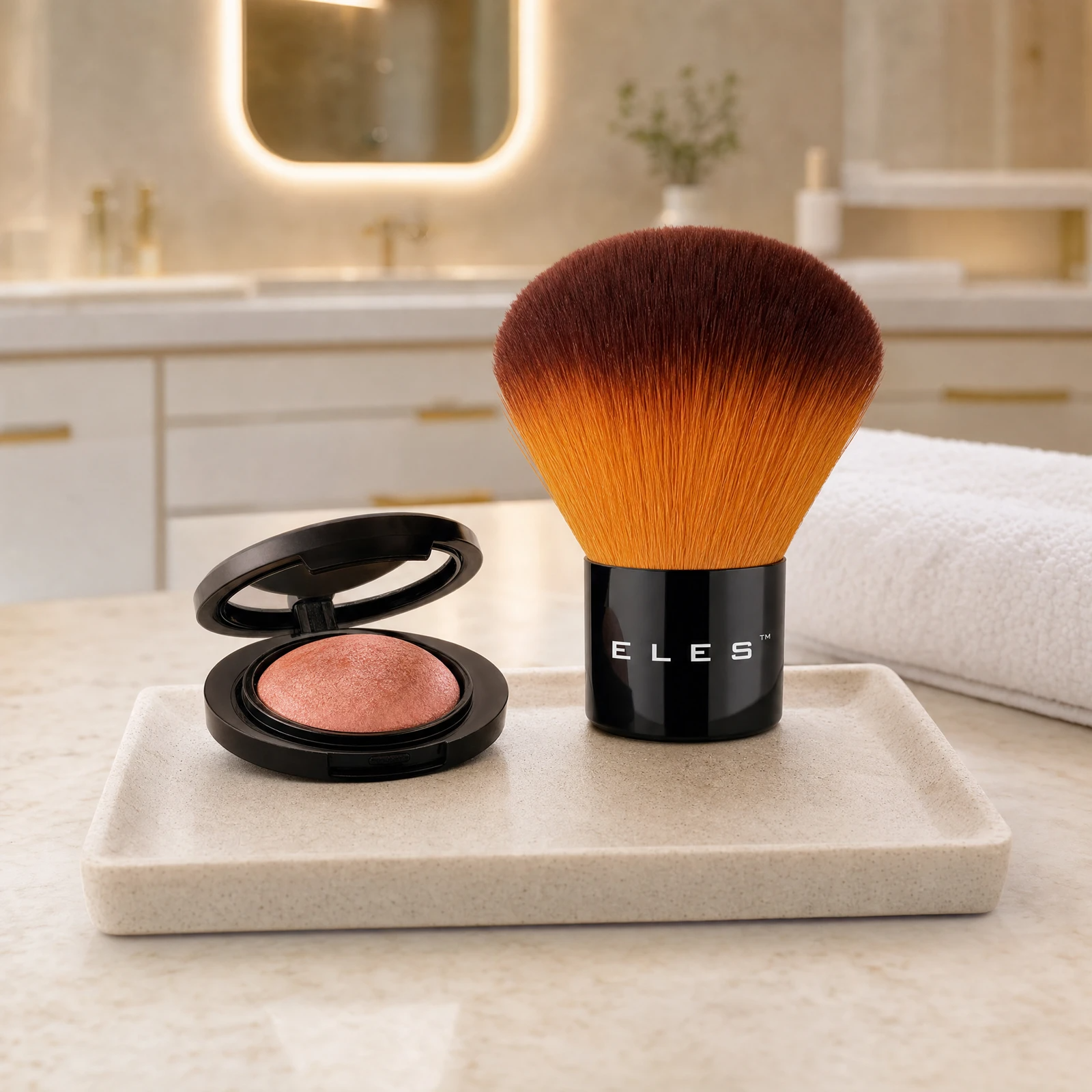 ELES Kabuki Brush with ombre amber bristles standing upright beside an open baked blush compact on a stone tray on a marble clinic bench inside a premium skin clinic treatment room