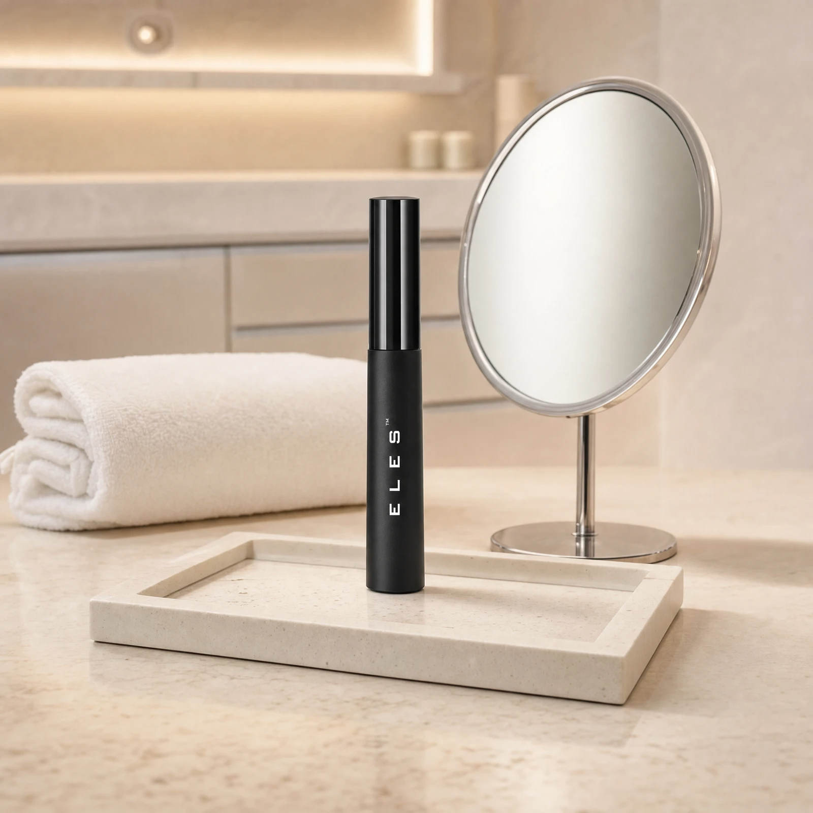 ELES Sensitive Eyes Mascara standing upright on a stone tray beside a round magnifying mirror on a marble clinic bench inside a premium skin clinic treatment room, ideal for professional lash finishing after facial treatments