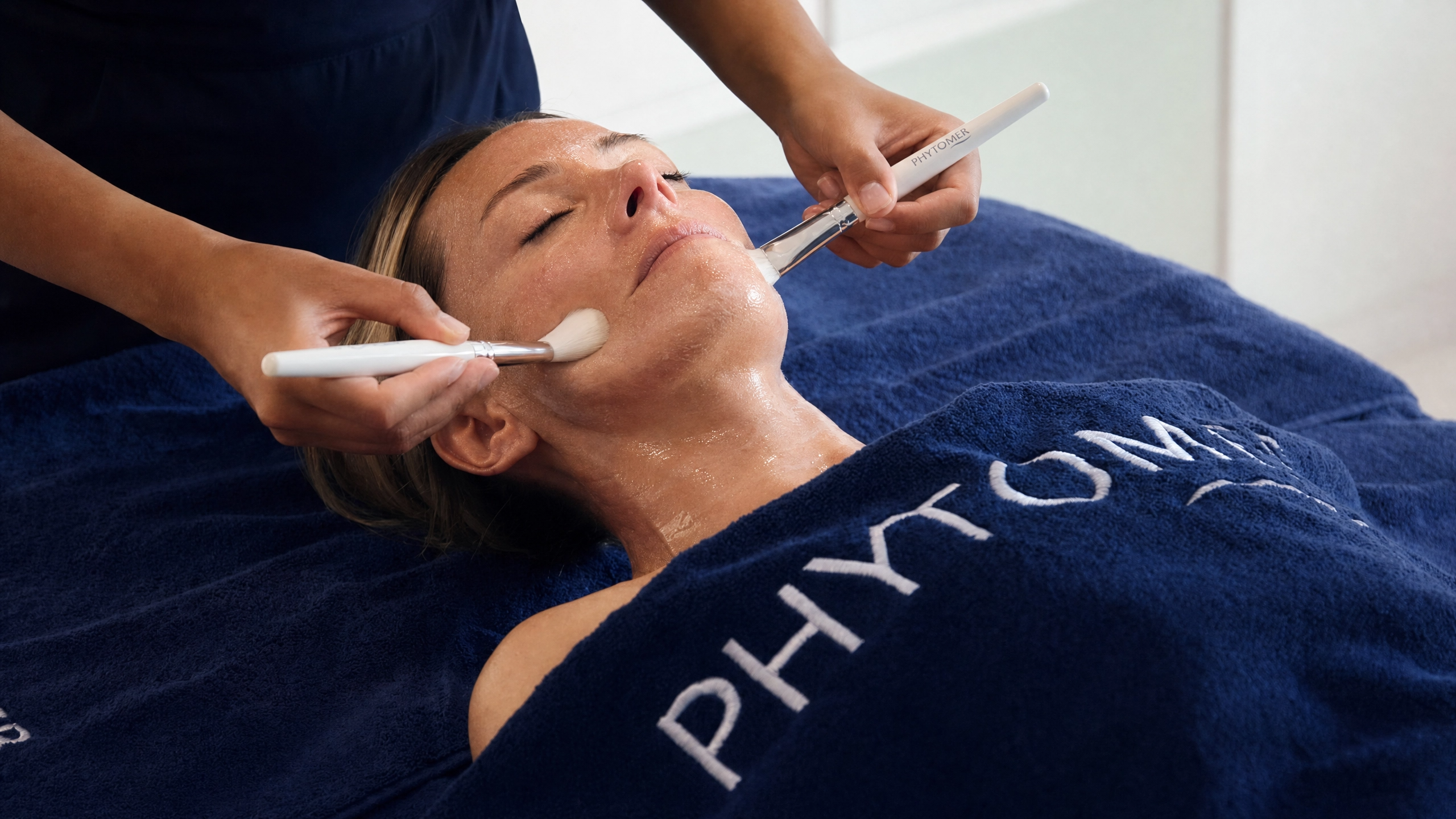 Phytomer professional facial treatment with therapist applying a skincare mask using brushes during a luxury spa facial treatment.