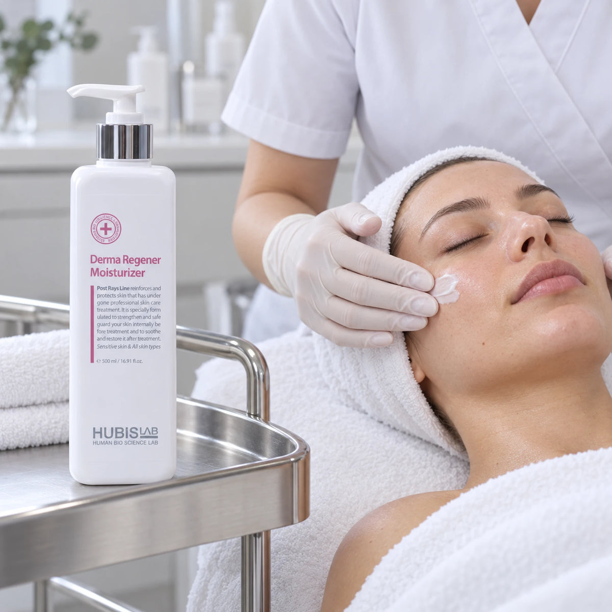Therapist applying HUBISLAB Derma Regener Moisturizer during a facial, with the professional 500 ml pump bottle on a tray.