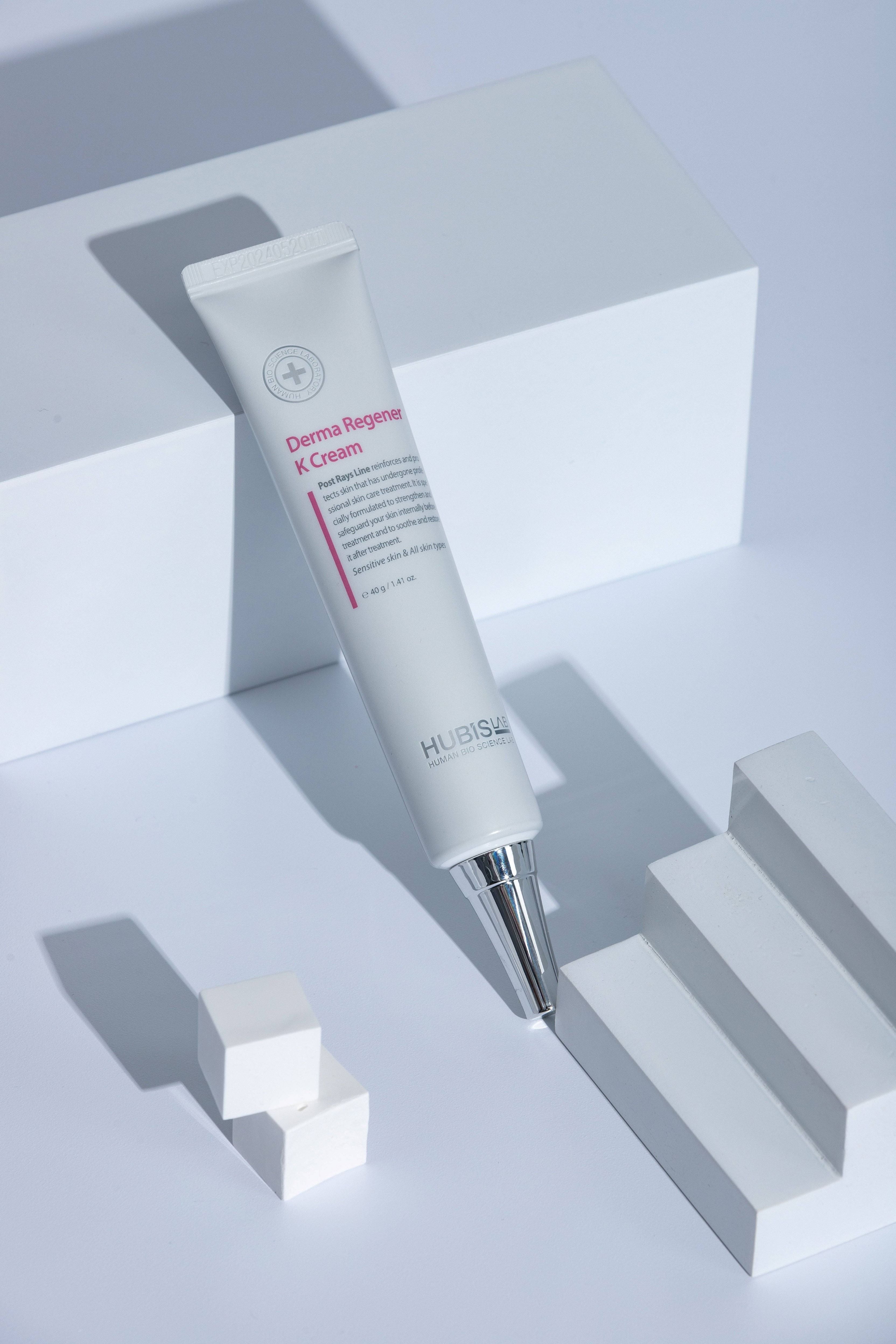 Post Rays Derma Regener K Cream by HUBISLAB Skincare cream tube with applicator on a light gray background