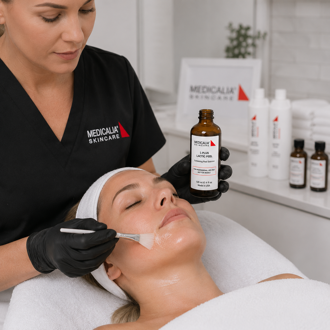Medicalia L+ Lactic Peel being applied with a brush during a professional facial treatment in a clean clinic treatment room.