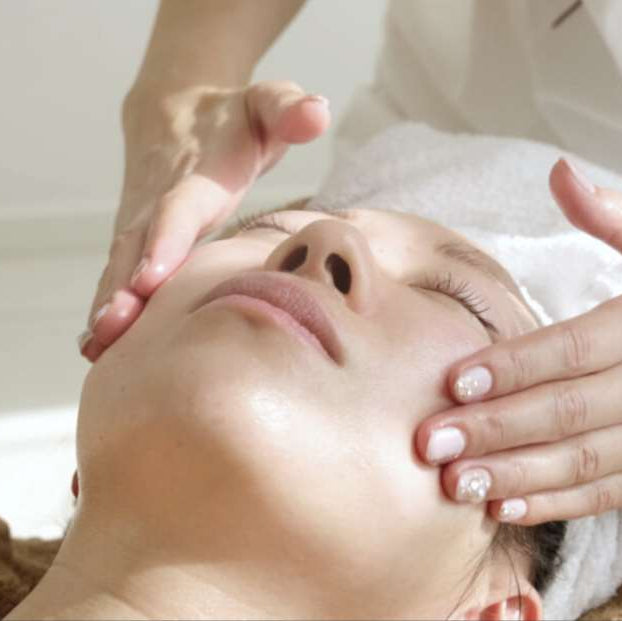 Person receiving a facial massage with a focus on skincare.