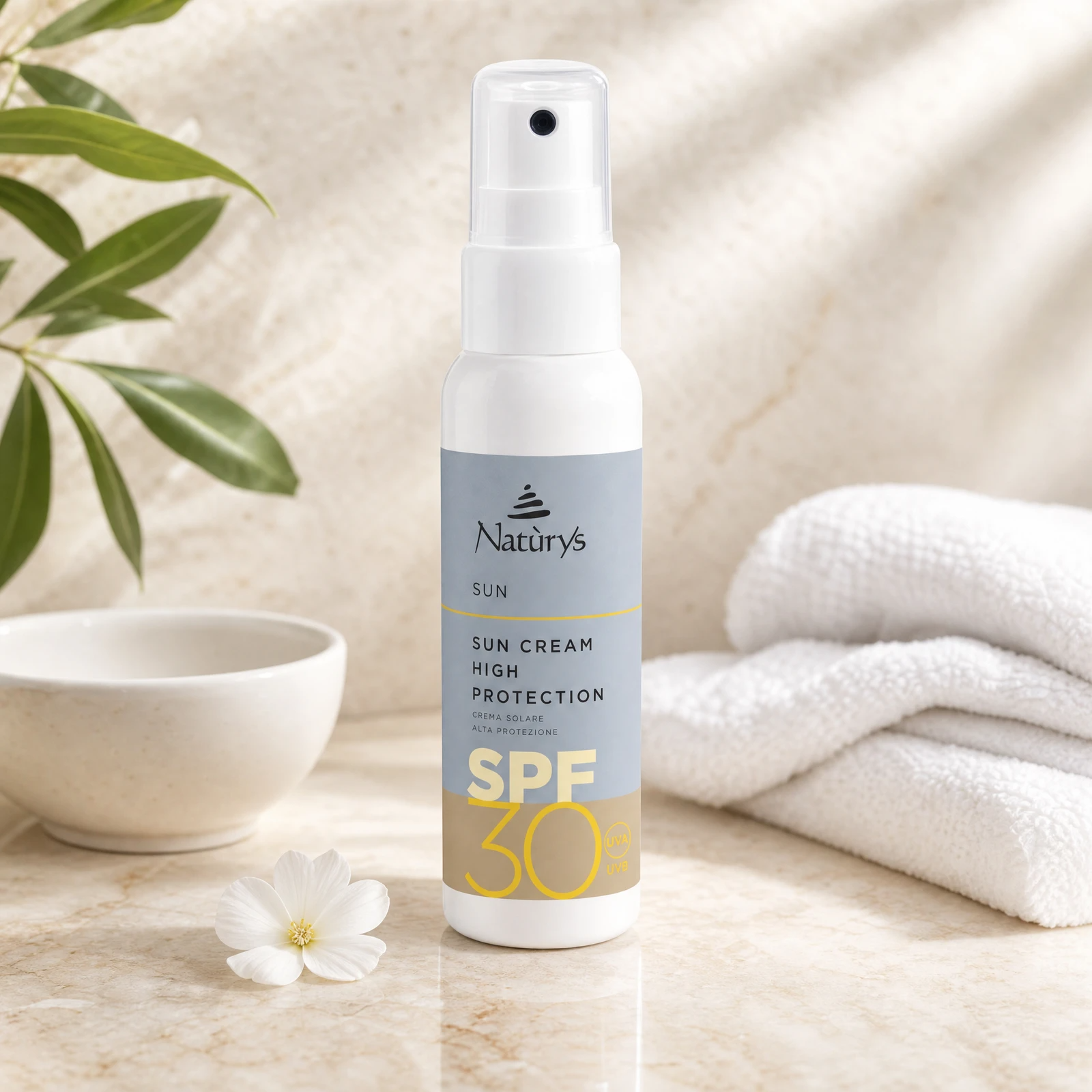Naturys Sun Cream High Protection SPF30 Spray 100ml white spray bottle on a warm stone vanity with tropical leaf and white flower for Beauty Collective consumer retail.