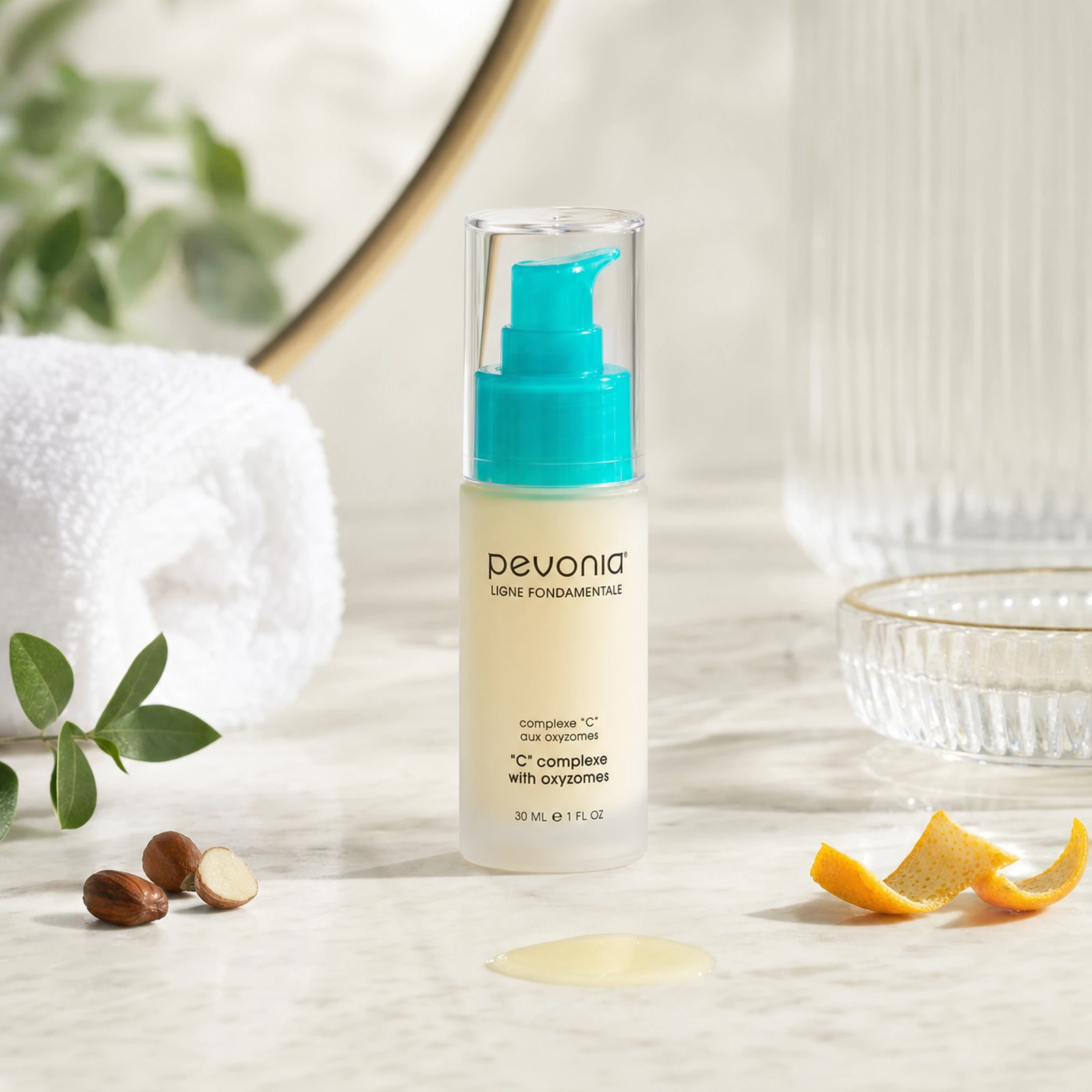 Pevonia C Complex with Oxyzomes 30ml lifestyle image displayed on a marble vanity with soft natural light, botanicals, citrus peel and serum texture.