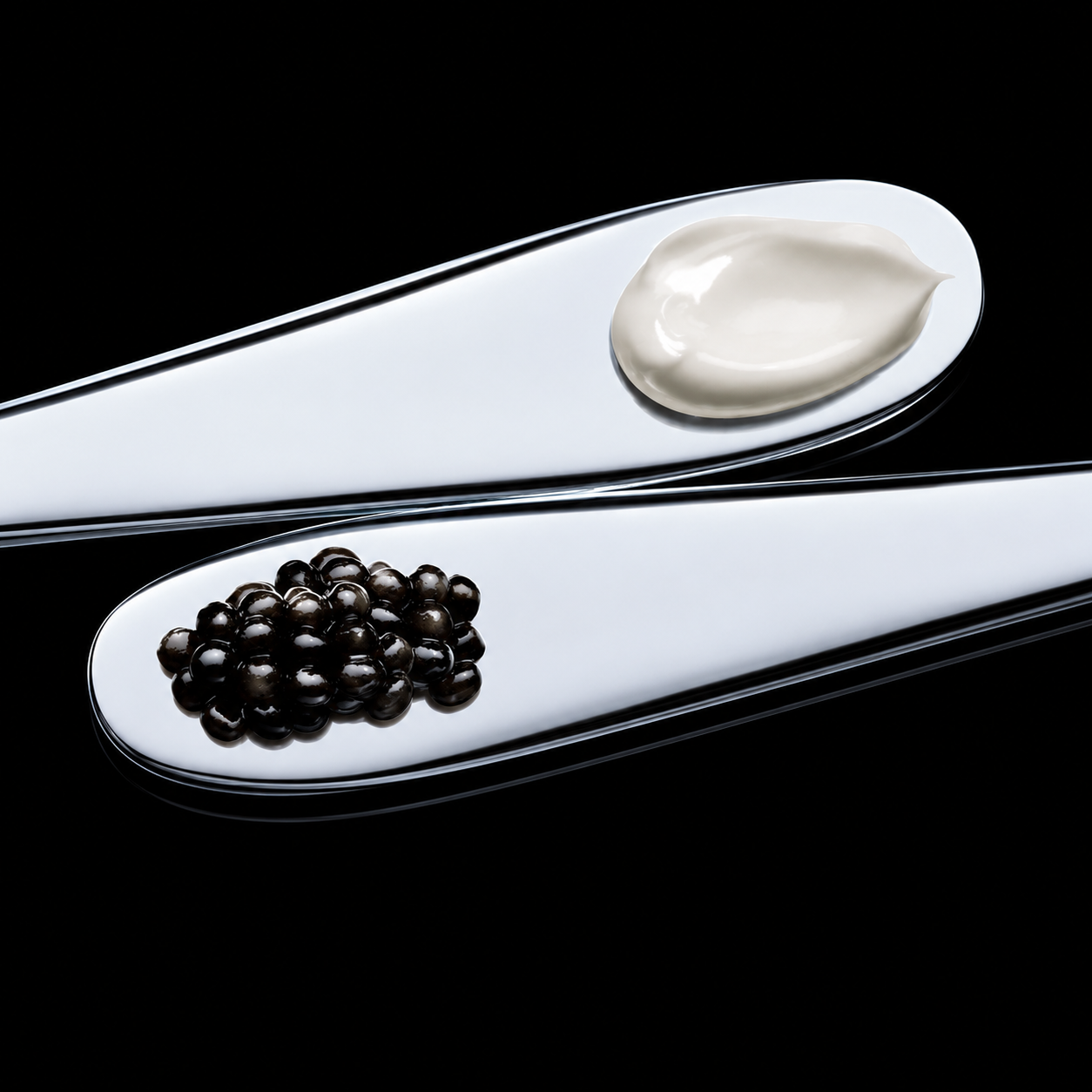 Two silver spoons with a scoop of cream and a pile of caviar on a black background