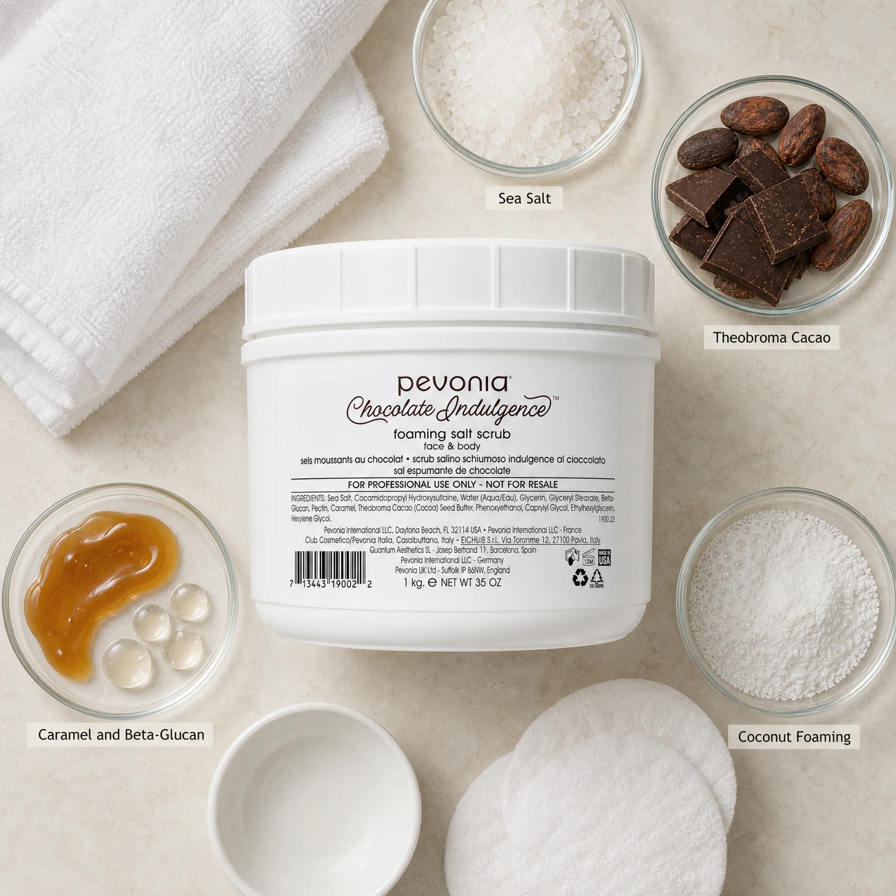 Pevonia Chocolate Indulgence Foaming Salt Scrub Face & Body 1kg ingredients flatlay with sea salt crystals, theobroma cacao, caramel and beta-glucan, and coconut foaming agents in clean glass petri dishes for professional B2B education.