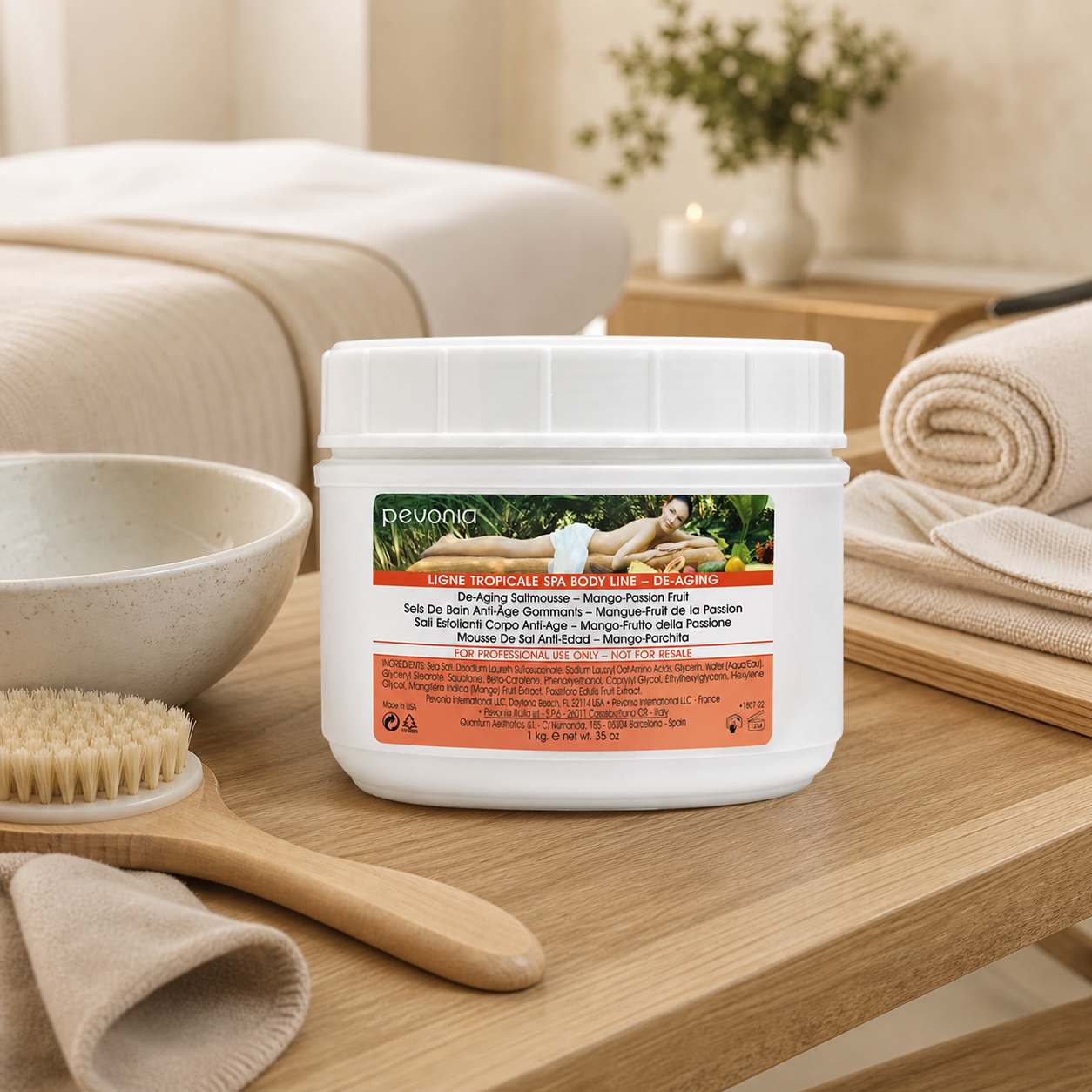 Pevonia De-Ageing Saltmousse Mango Passionfruit 1kg jar displayed in an upmarket day spa body treatment room with unbranded treatment accessories.