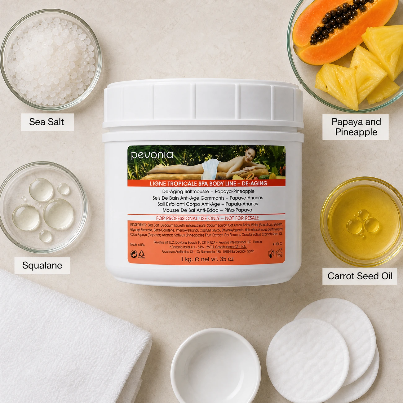 Pevonia De-Aging Saltmousse Papaya-Pineapple 1kg ingredients flatlay with sea salt crystals, fresh papaya and pineapple, squalane, and carrot seed oil in clean glass petri dishes for professional B2B education.
