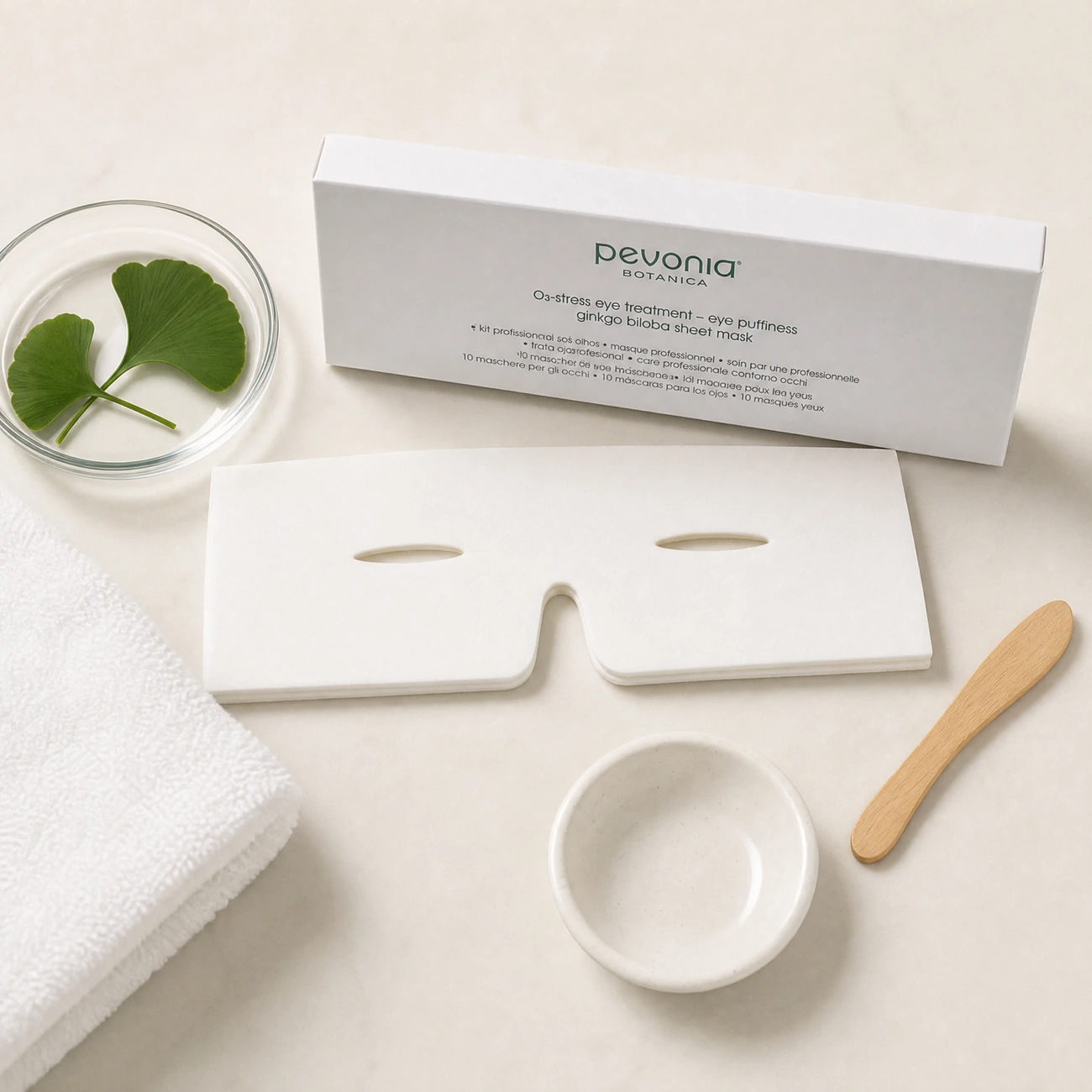 Pevonia De-Stress Eye Puffiness Ginkgo 10pk treatment-support flatlay with Ginkgo Biloba leaves, professional eye mask and clinic treatment accessories.
