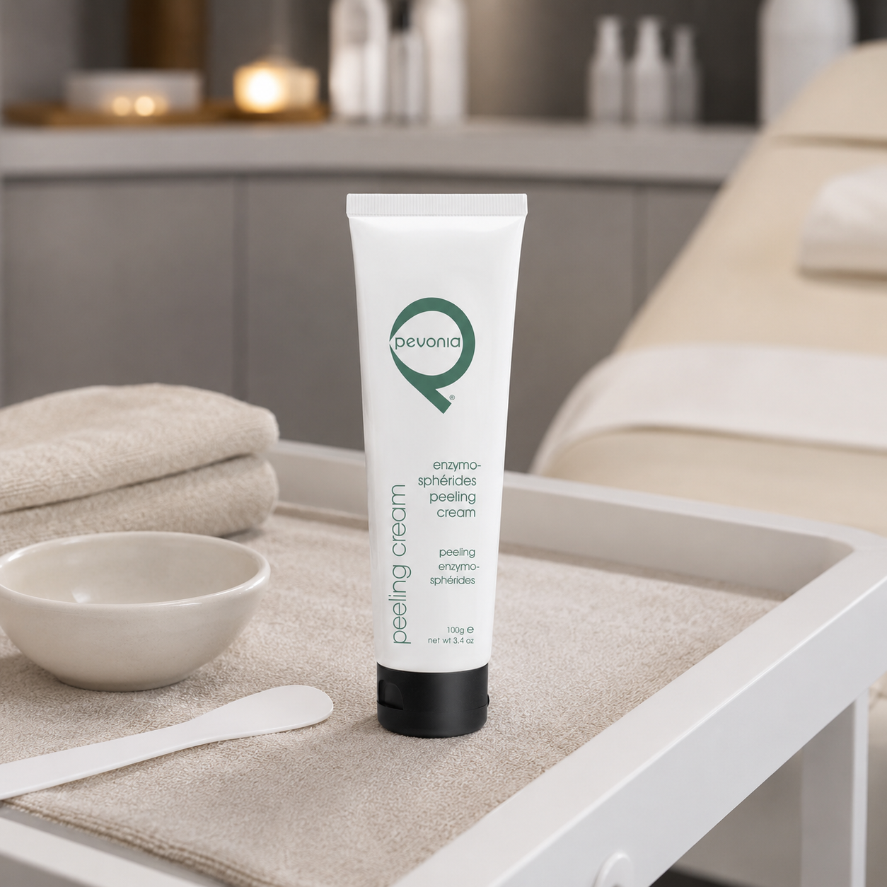 Pevonia Enzymo-Spherides Peeling Cream 100g tube displayed on a therapist trolley in a day spa facial treatment room with unbranded treatment accessories.