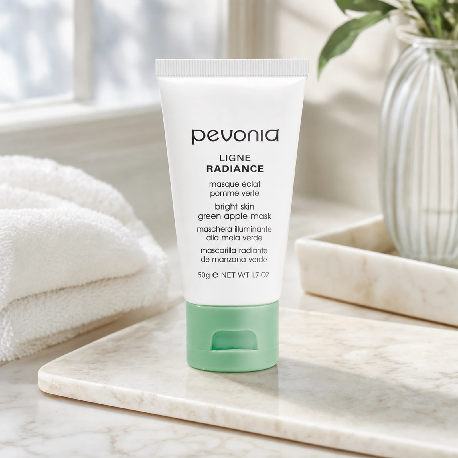 Pevonia Green Apple Mask 50g lifestyle image displayed on a marble vanity with soft natural light, towel and botanical styling.