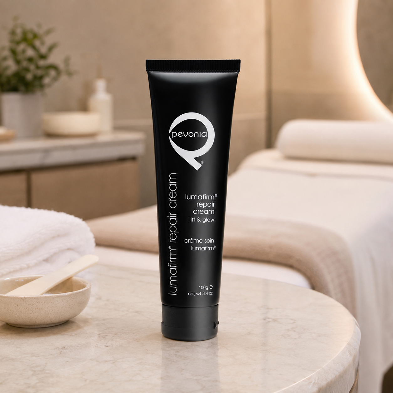 Pevonia Lumafirm Repair Cream Lift and Glow 100g tube displayed in an upmarket day spa treatment room with unbranded skincare treatment accessories.