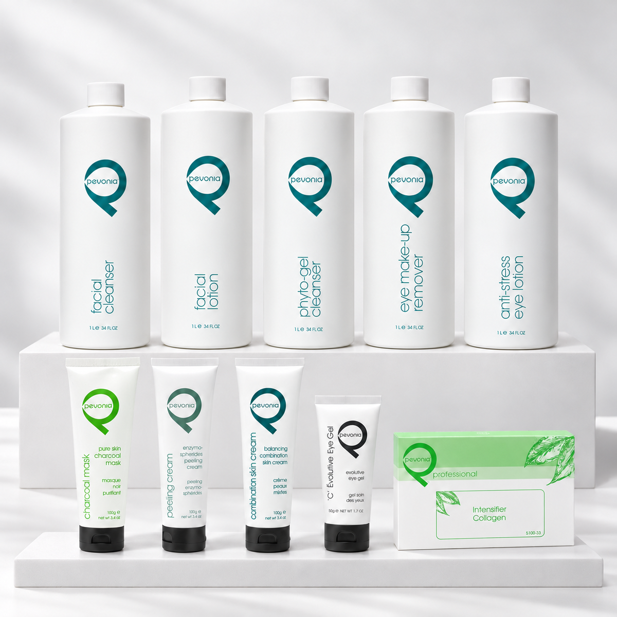 Ten Pevonia Radiance Pure Skin Charcoal professional treatment products arranged on white display tiers, including Charcoal Mask 100 g, Balancing Combination Skin Cream 100 g and a Collagen Intensifier 5 × 5 ml professional ampoule box.