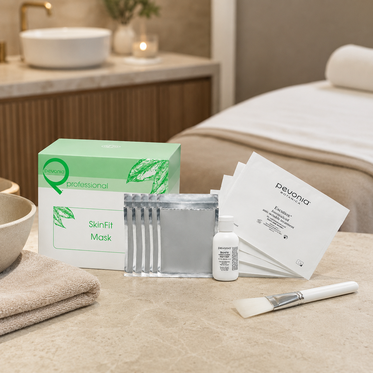Pevonia SkinFit Mask box and treatment components beside a mixing bowl, towel and mask brush in a treatment room.