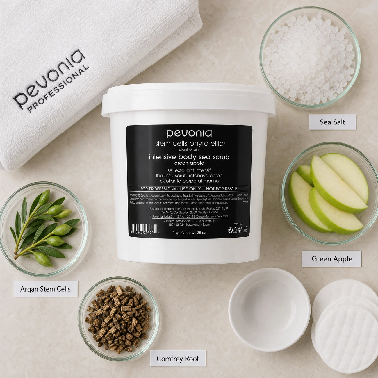 Pevonia Stem Cells Phyto-Elite Intensive Body Sea Scrub Green Apple 1kg ingredients flatlay with sea salt crystals, green apple, argan stem cells, and comfrey root in clean glass petri dishes for professional B2B education.