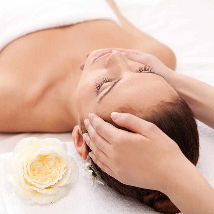 A person receiving a facial treatment with a focus on a flower.