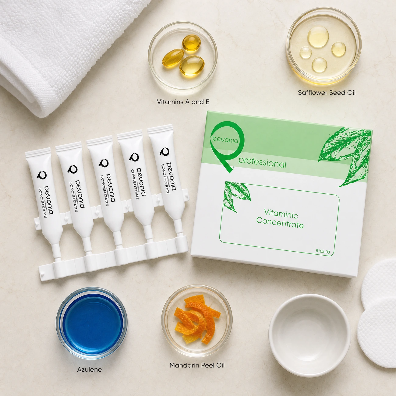 Pevonia Vitaminic Concentrate ingredients flatlay with Vitamins A and E, safflower seed oil, blue azulene, and mandarin orange peel oil in clean glass petri dishes for professional B2B education.