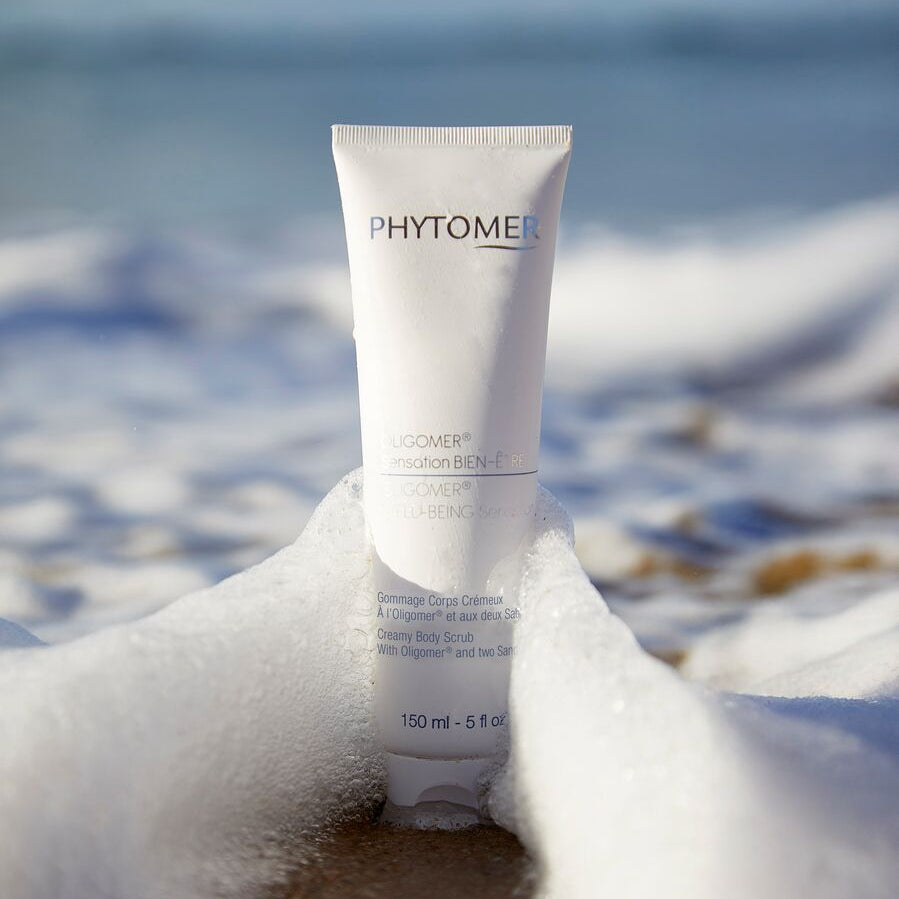 Tube of Phytomer Body scrub on a beach with ocean in the background