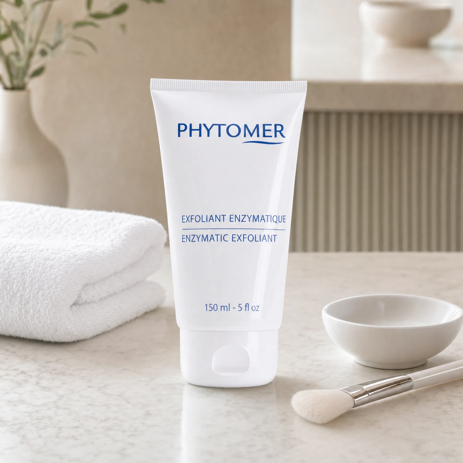 Phytomer Enzymatic Exfoliant 150ml professional tube on a premium beauty clinic treatment counter with white spa towel, ceramic bowl and facial brush
