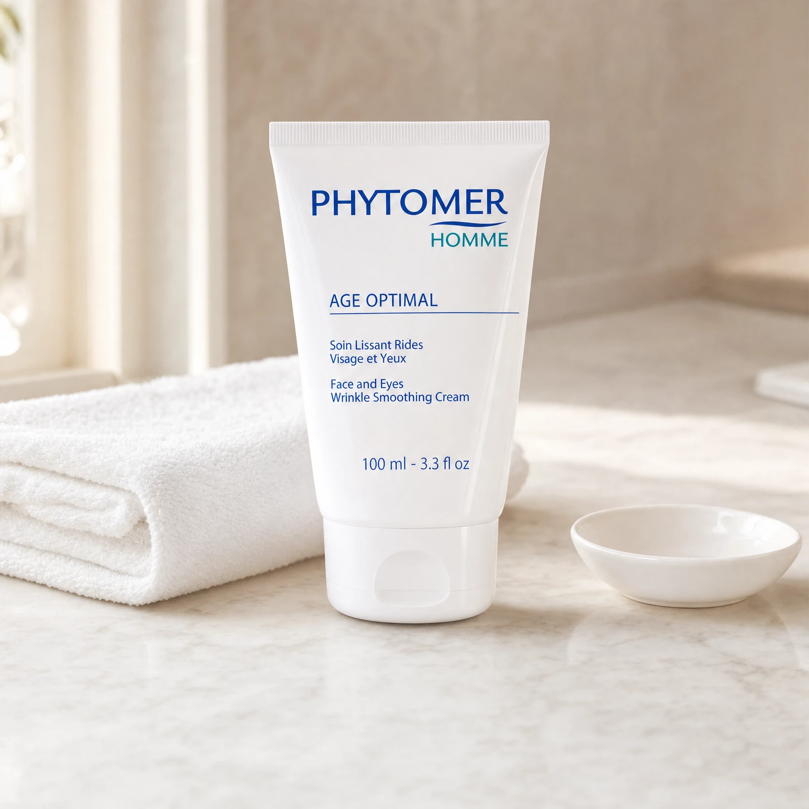 Phytomer Homme Age Optimal Face and Eyes Wrinkle Smoothing Cream 100ml professional tube on a premium men's grooming clinic marble counter with white towels and ceramic dish