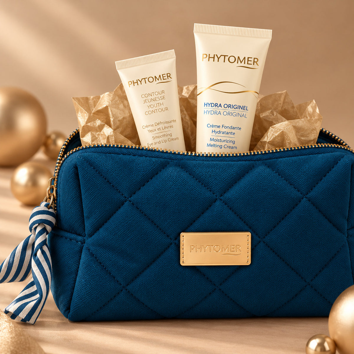PHYTOMER Hydra Original Ritual Gift Set with Hydra Original Moisturising Melting Cream and Youth Contour Eye and Lip Cream emerging from a blue quilted cosmetics pouch.