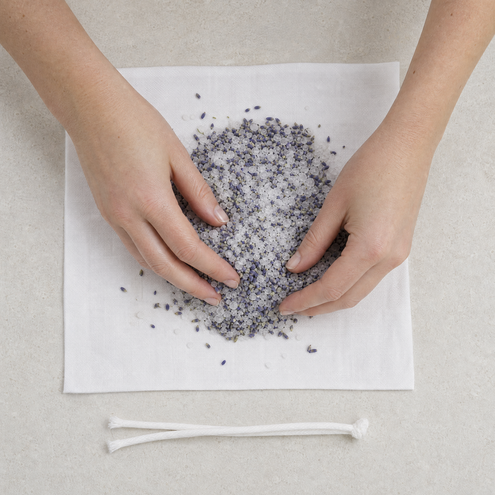 Therapist mixing Marine Salt Crystals and Lavender Flowers on a fabric square to prepare a Phytomer Marine Bolus