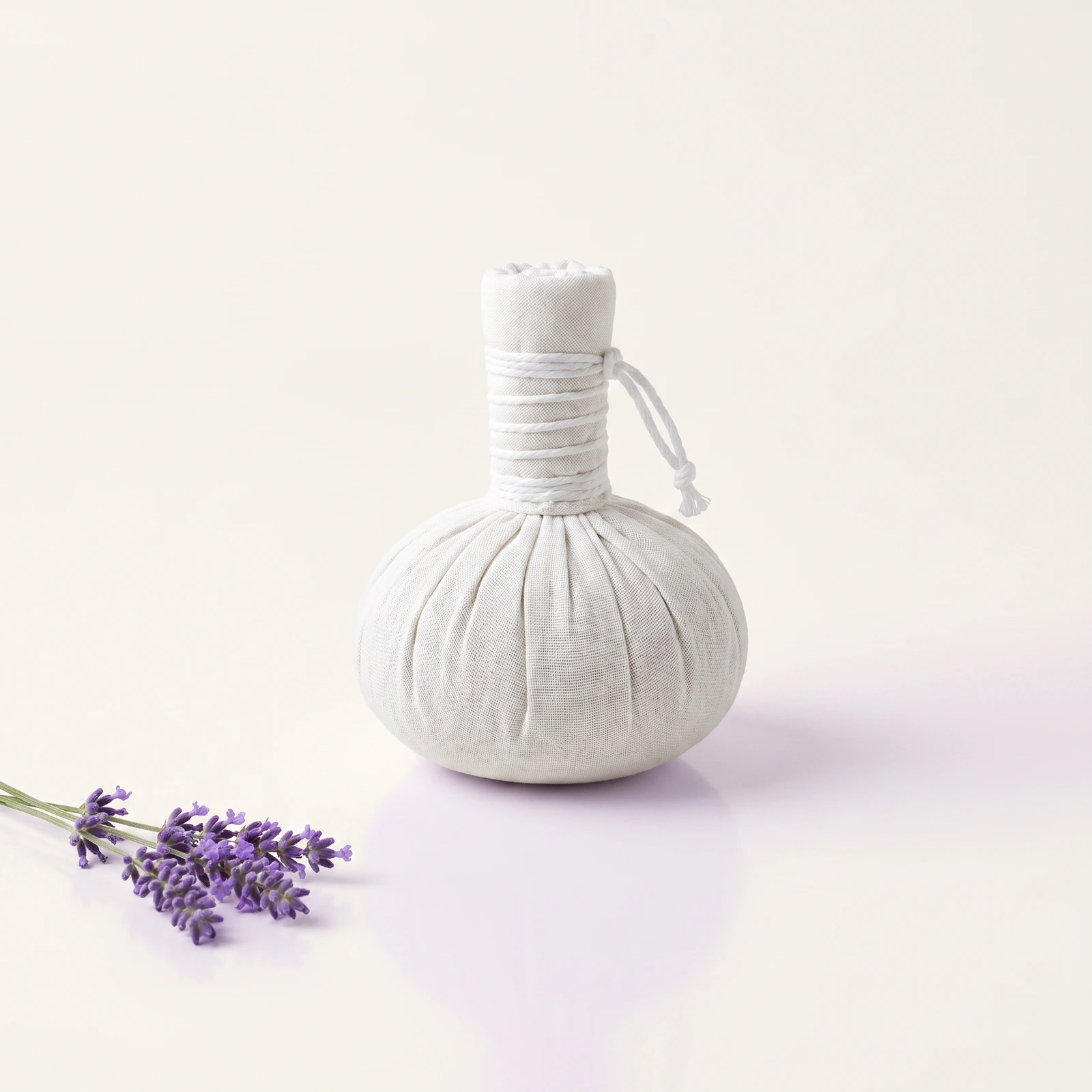 White linen marine bolus with lavender on a warm-white professional spa background.