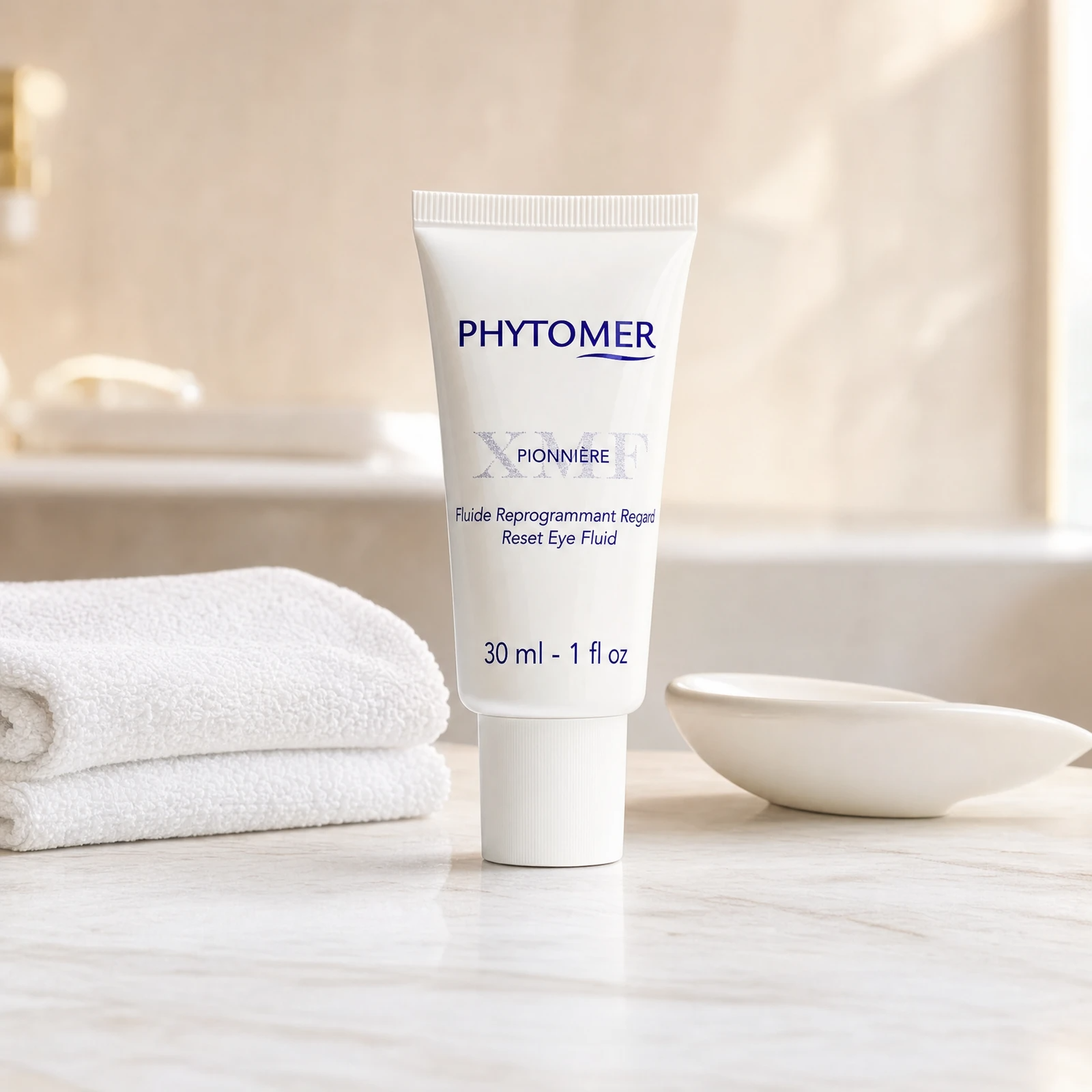 Phytomer Pionniere XMF Reset Eye Fluid 30ml professional tube on a premium beauty clinic marble counter with white spa towels and ceramic dish