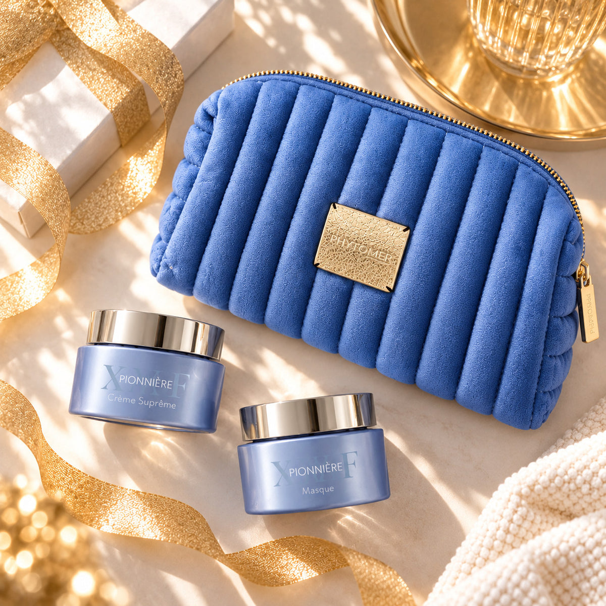 PHYTOMER Pionnière XMF Ritual Gift Set with blue cosmetics pouch, Supreme Cream and mask jars arranged with festive gold ribbon.