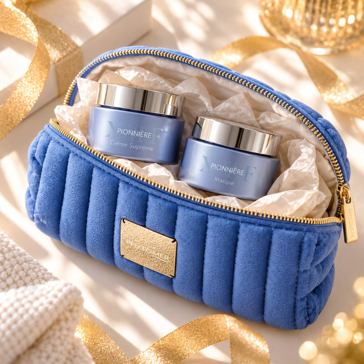 PHYTOMER Pionnière XMF Supreme Cream and mask jars nestled inside an open blue cosmetics pouch with gold accents.