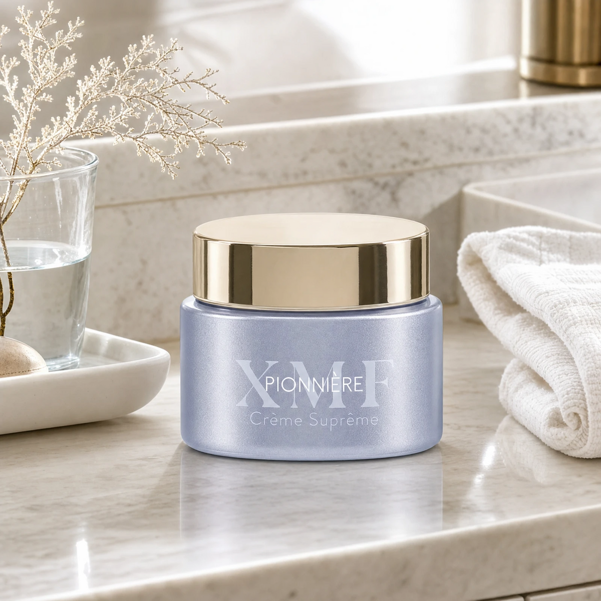 Phytomer Pionniere XMF Youth and Glow Supreme Cream on a marble bathroom counter with gypsophila in glass carafe, white ceramic tray with sea pebble, white waffle towel and gold bathroom accessory, premium at-home skincare setting